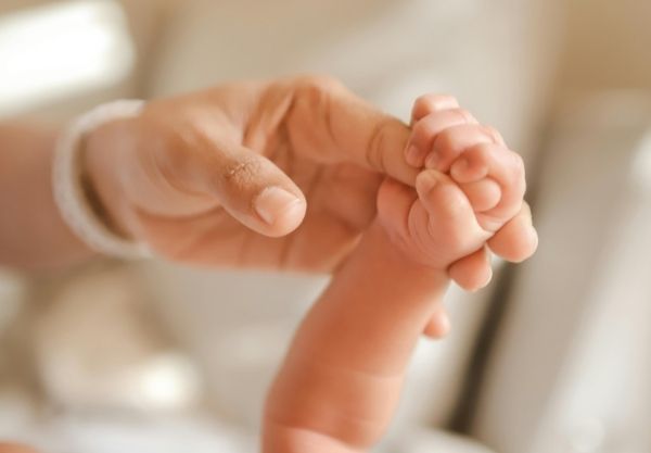 Neugeborenes hält Hand der Mutter fest