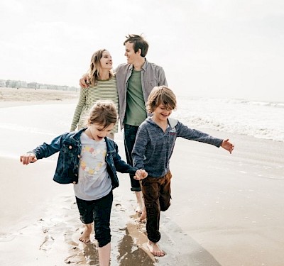 Familie mit hämophilen Kindern läuft am Strand entlang