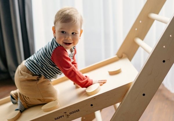 Kind klettert und krabbelt auf Spielturm