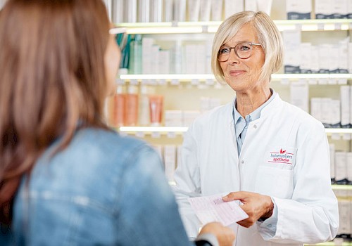 Apothekerin nimmt Rezept für Herzmedikamente entgegen