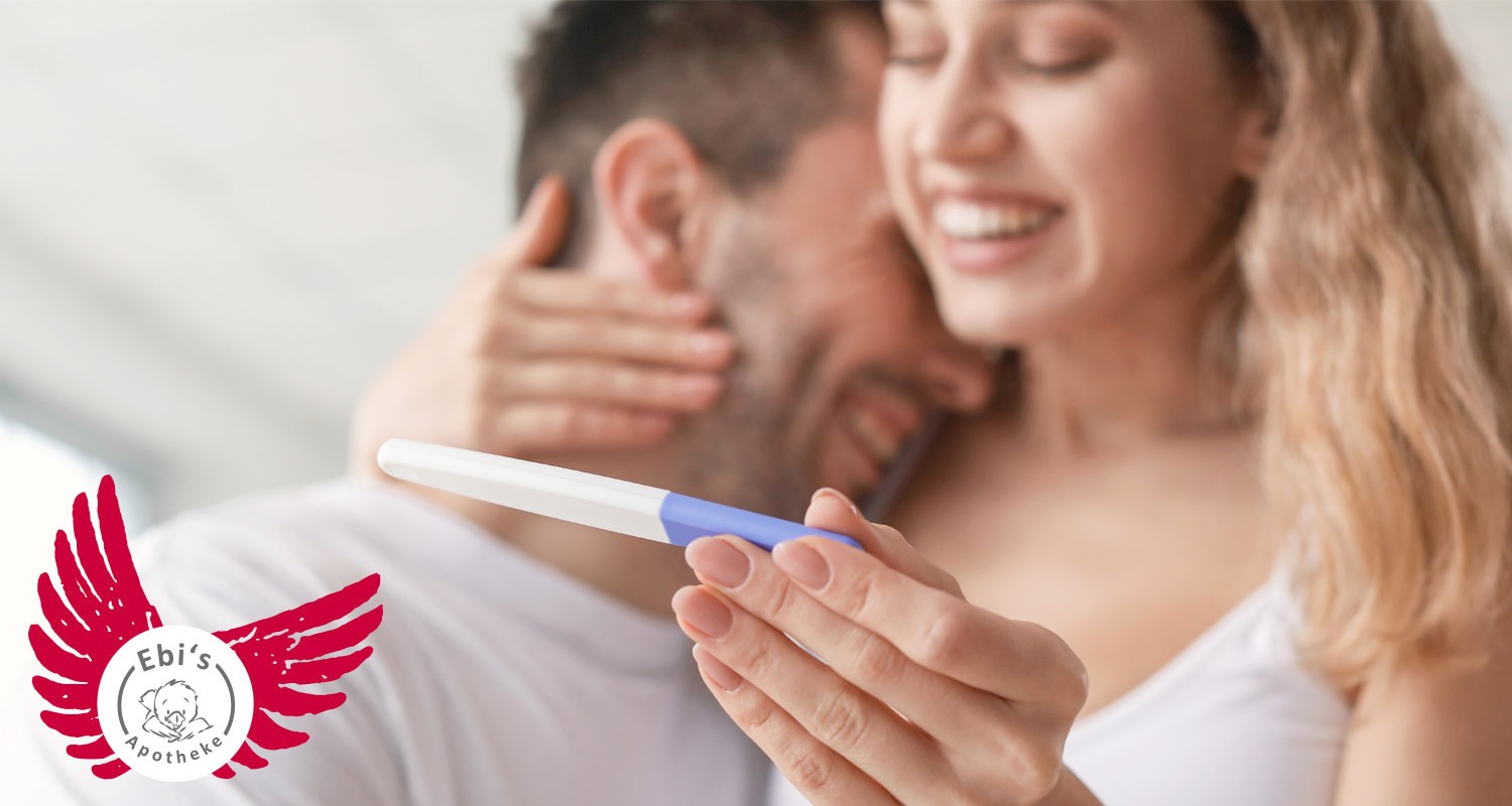 Frühe Schwangerschaftsanzeichen: Lachendes Paar freut sich über positiven Schwangerschaftstest