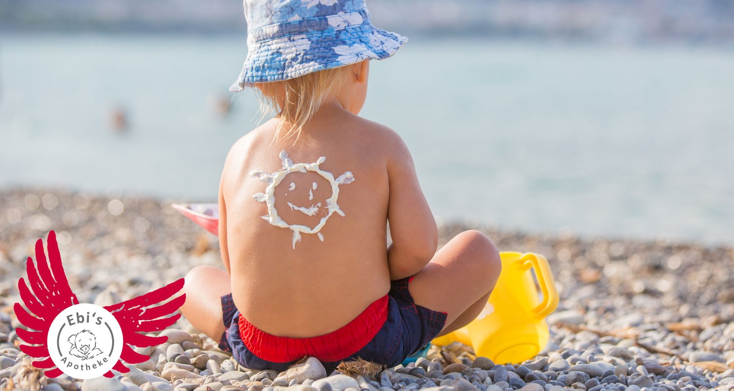 Sonnenstich bei Kindern: Kind mit Sonnencreme auf dem Rücken spielt am Strand